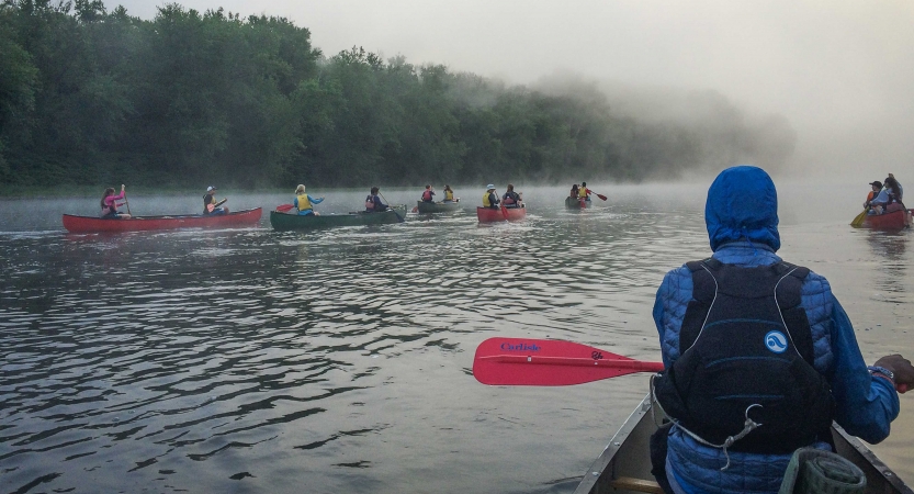 a group of canoes are paddled into fog on an outward bound veterans trip